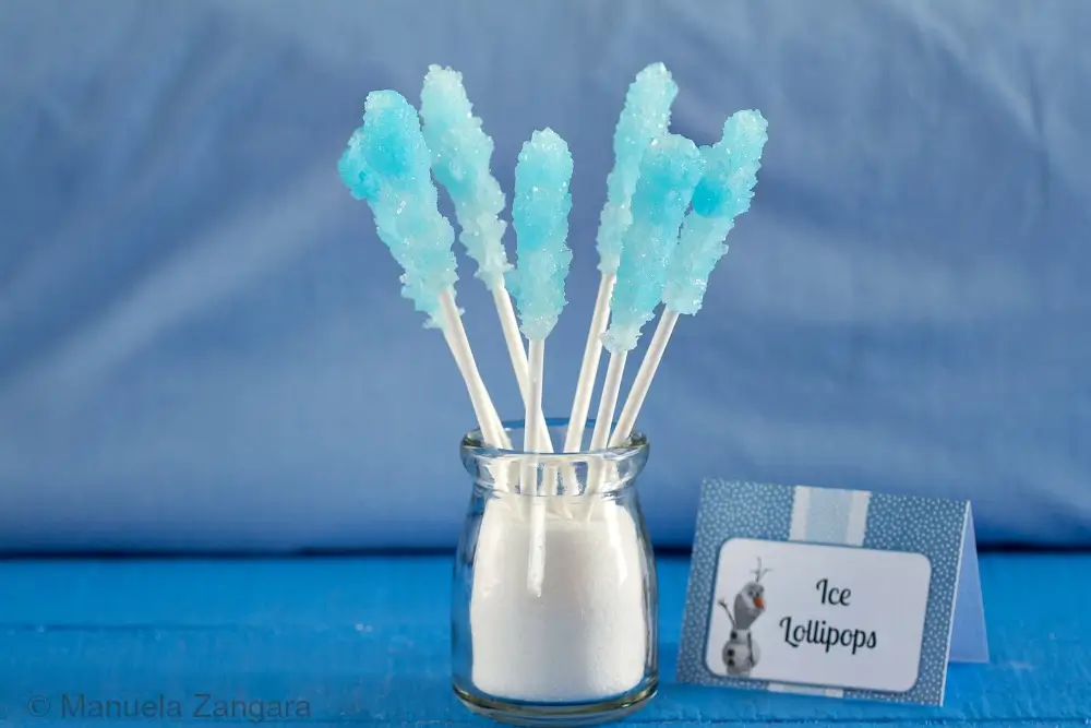 Blue rock candy lollipops displayed in a jar beside a Frozen-themed label.