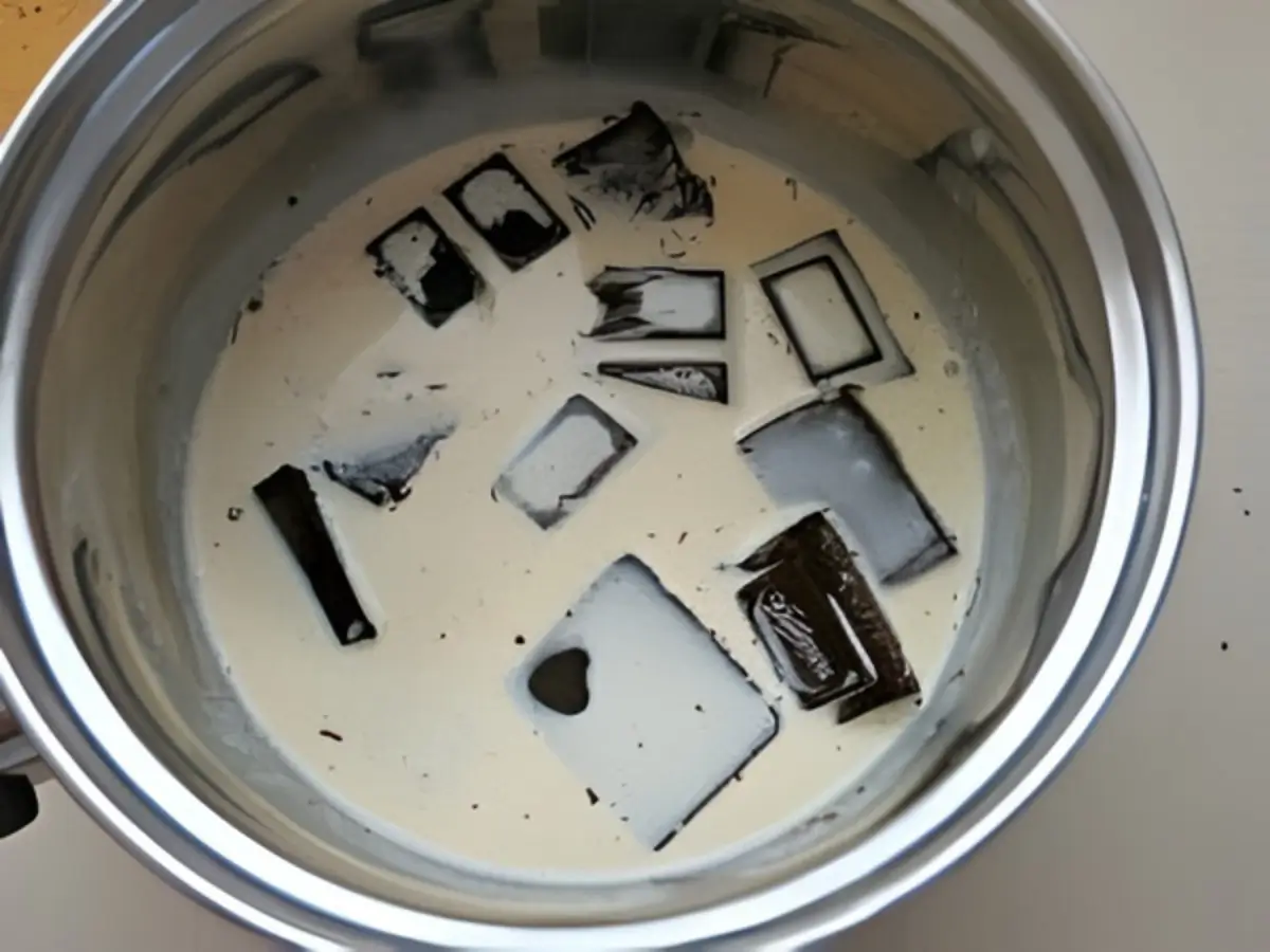 Chocolate pieces melting in heavy cream inside a stainless steel saucepan for the chocolate sauce.