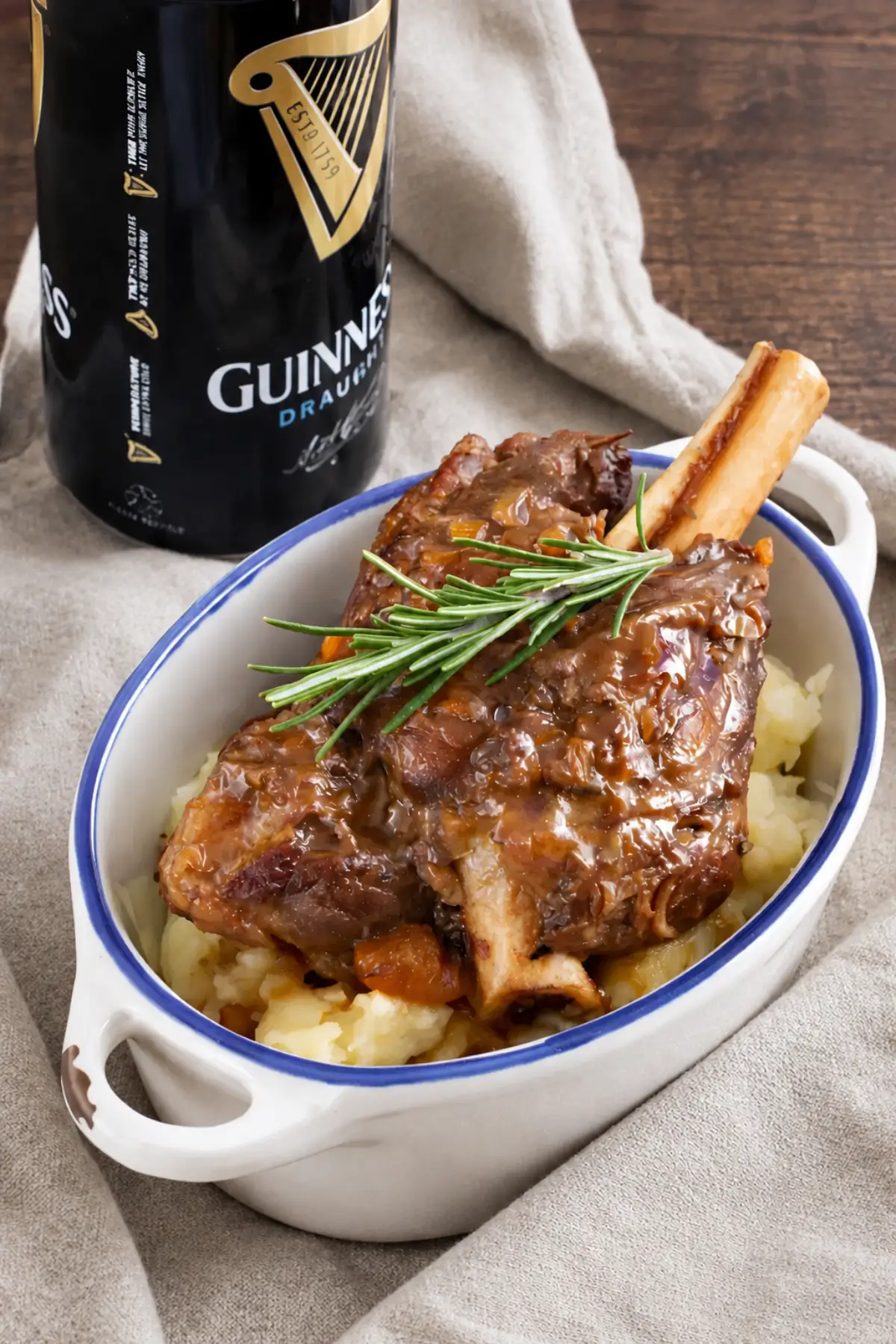 Braised lamb shank served over mashed potatoes with rich gravy in a baking dish.