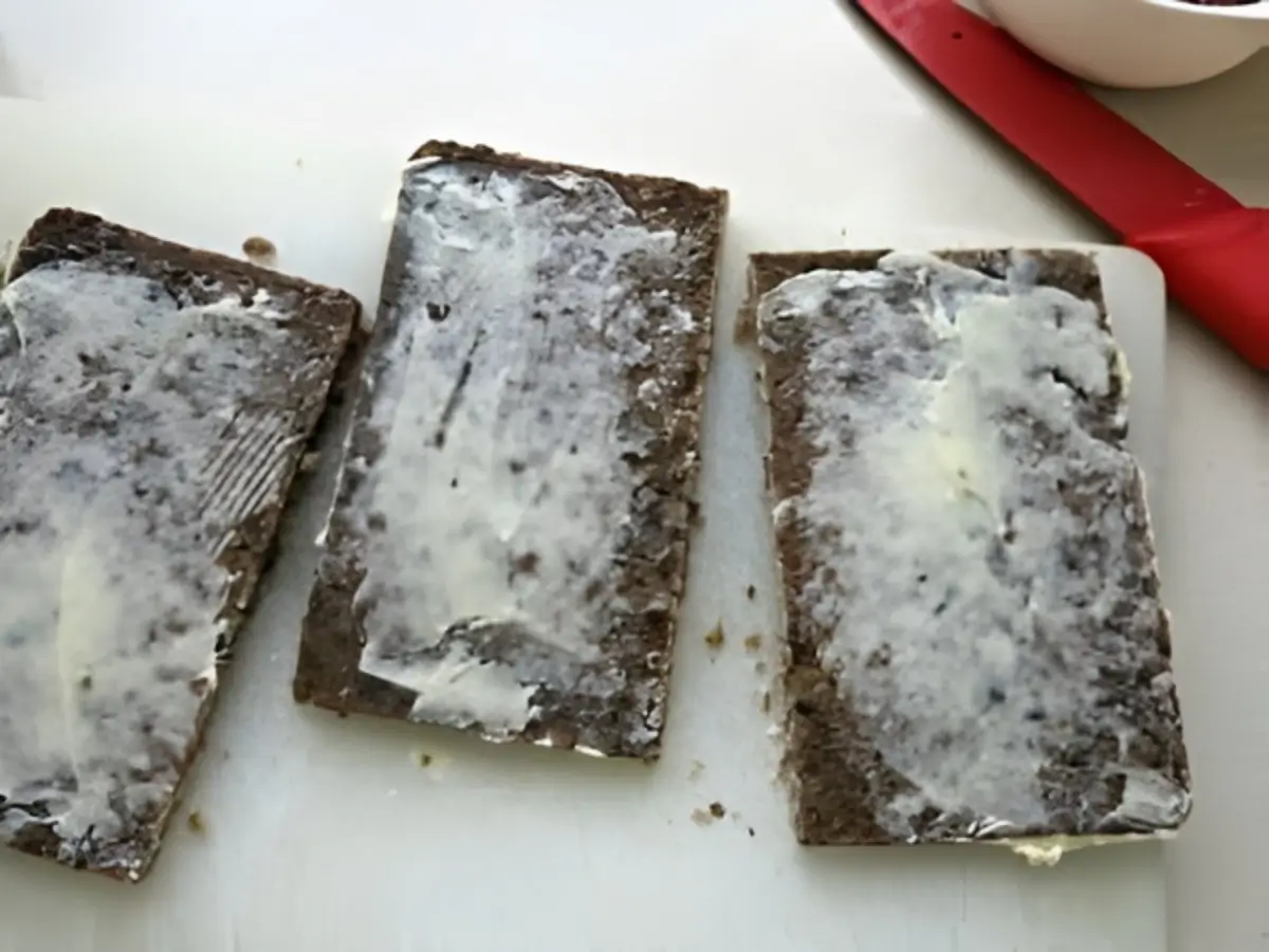 Buttered slices of dark rye bread ready for assembling traditional Scandinavian Smørrebrød.