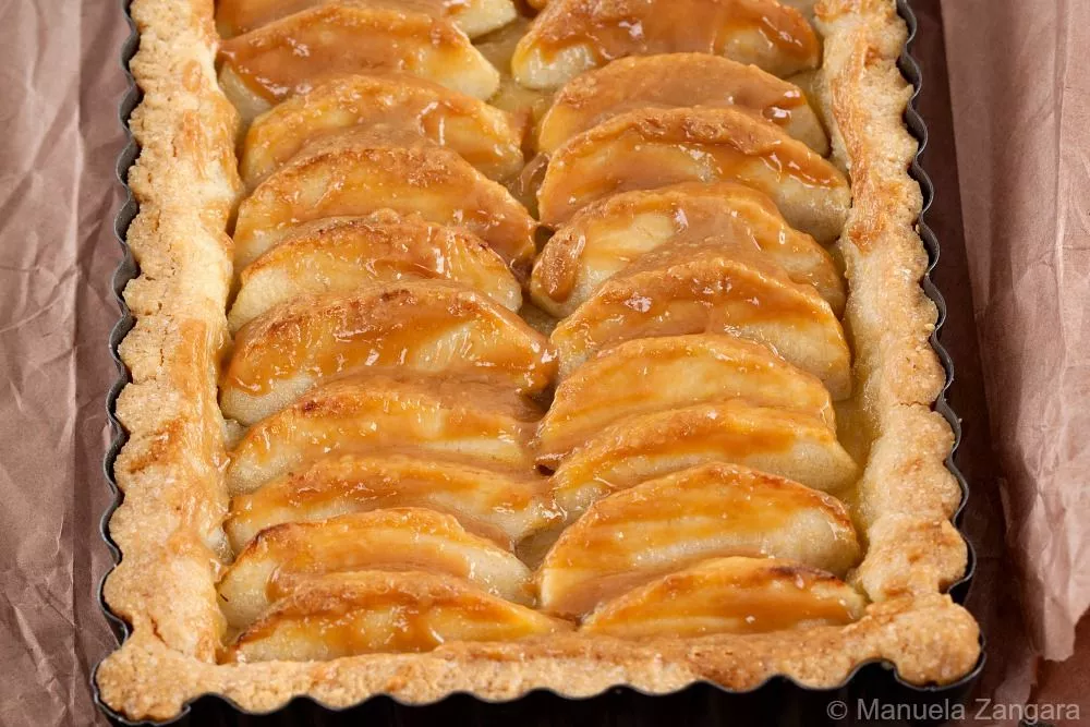 Close-up of golden apple slices brushed with Dulce de Leche in the baked tart.