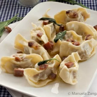 Plate of Casoncelli alla Bergamasca topped with crisp pancetta and sage butter sauce.