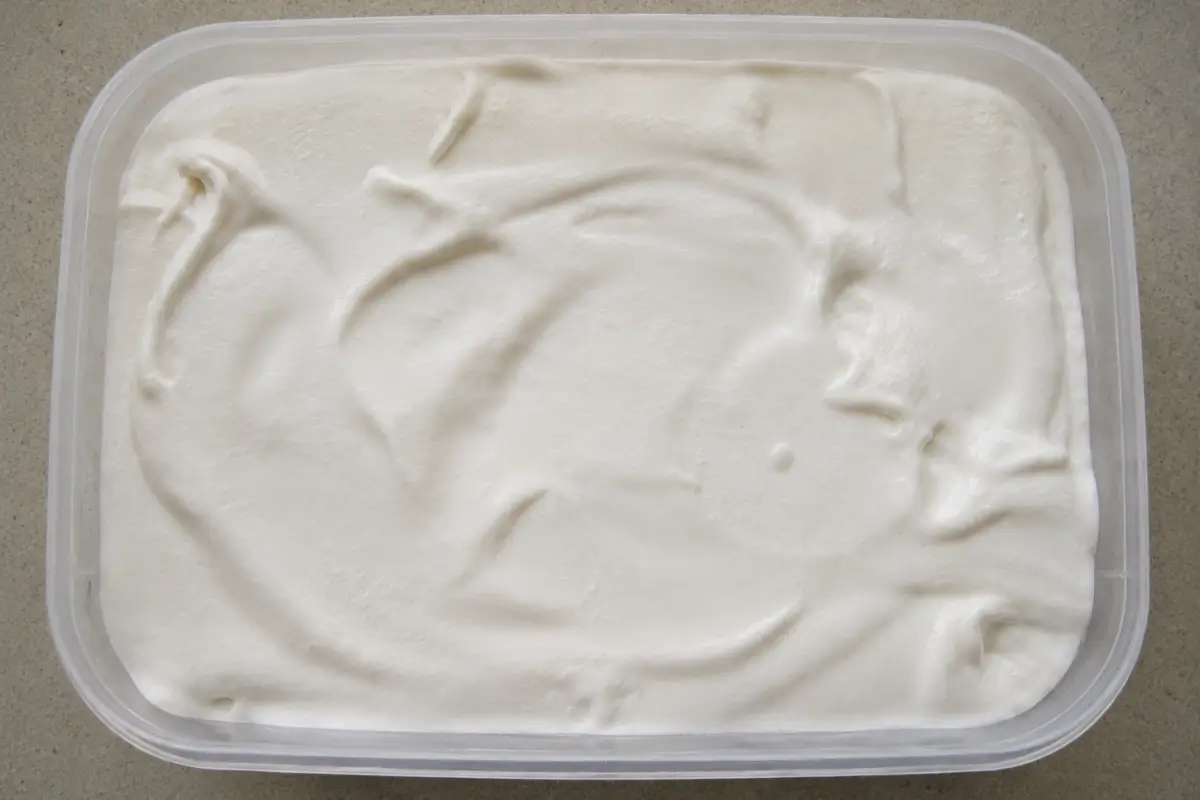 Freshly churned coconut ice cream smoothed into a storage container before freezing.
