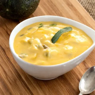 Close up of passion fruit sauce with herbs in a white bowl.
