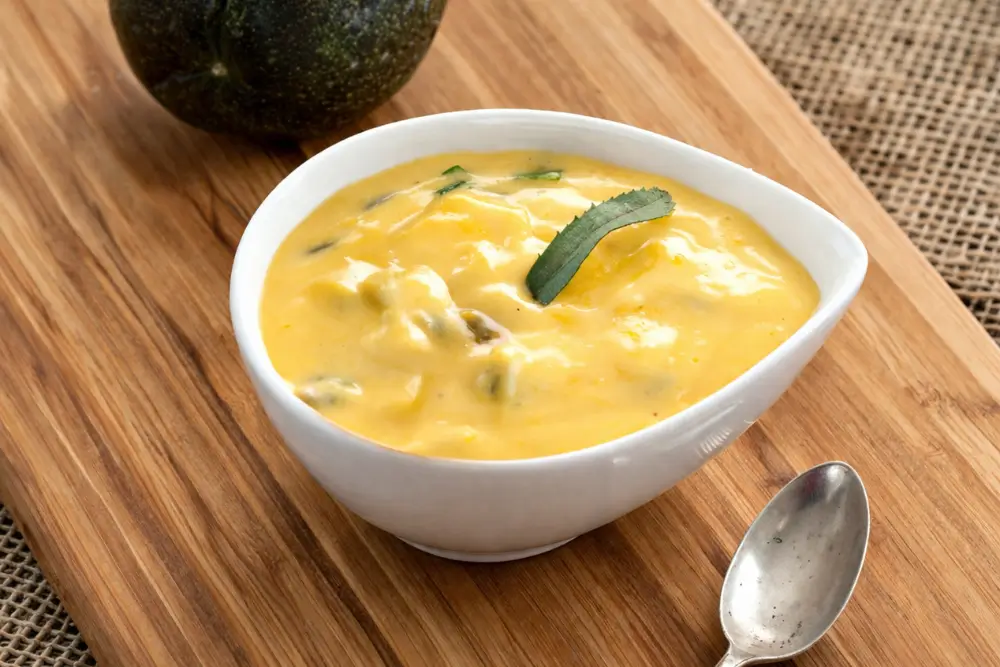 Close up of passion fruit sauce with herbs in a white bowl.