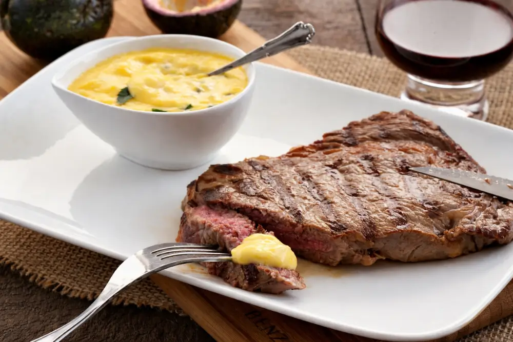 Sliced medium rare steak with sauce on a white plate.