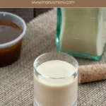 Glass of salted caramel liqueur with jar of caramel sauce and bottle in the background.