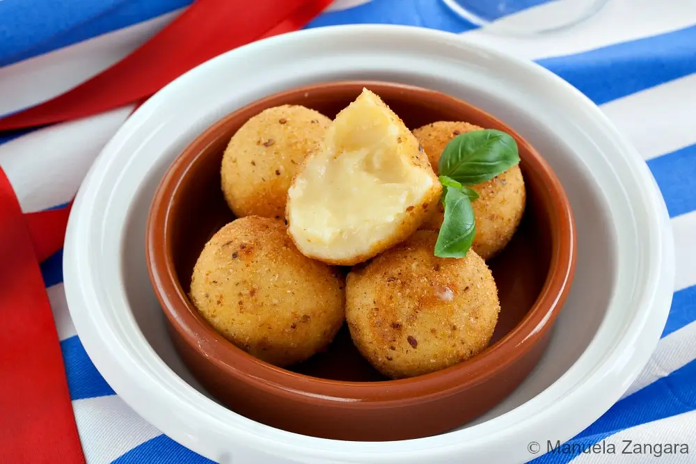 Close-up of fried cheese bitterballen with crisp coating.