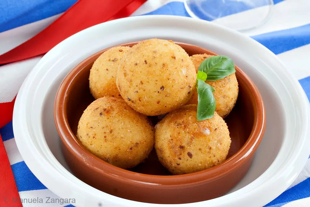 Golden fried cheese bitterballen served in a bowl.