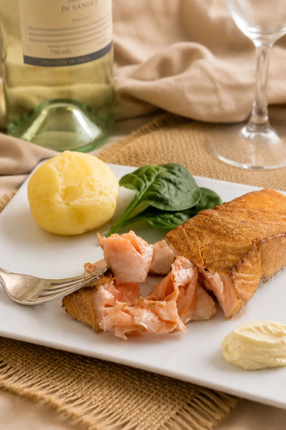 Hot smoked salmon fillet served with boiled potato and aioli on a white serving plate.