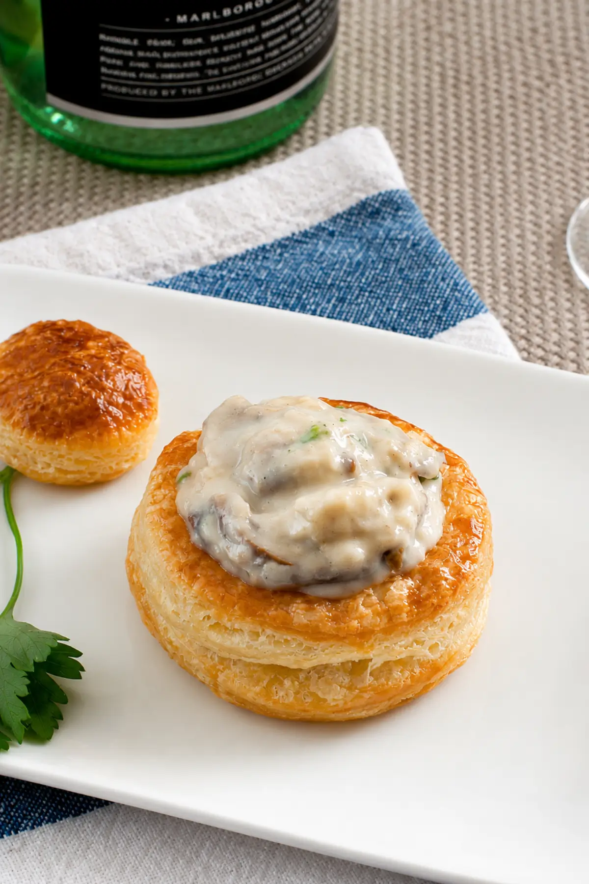 Filled vol au vents served with fresh parsley on a white plate.