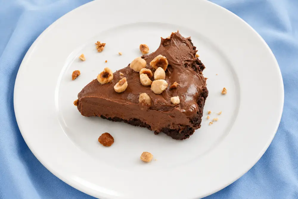Slice of Nutella and Mascarpone Pie topped with chopped toasted hazelnuts.