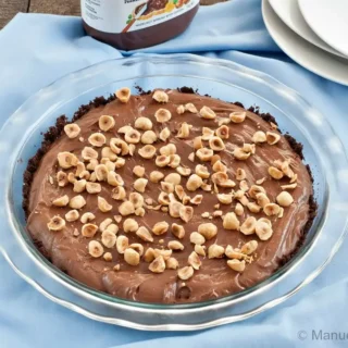 Nutella and Mascarpone Pie in a glass dish topped with chopped toasted hazelnuts.