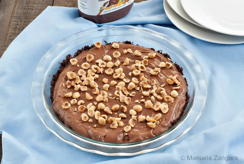 Nutella and Mascarpone Pie in a glass dish topped with chopped toasted hazelnuts.