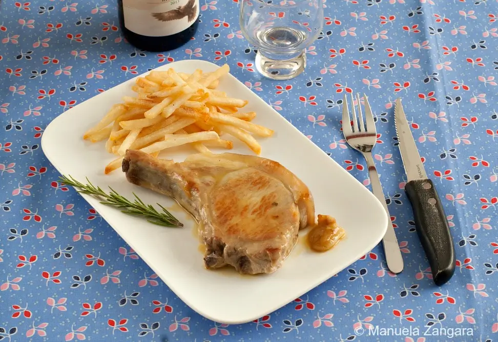 Pan-Fried Pork Loin Cutlet plated with fries and rosemary on a white dish.