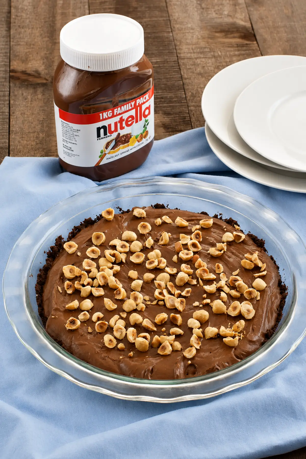 Chocolate hazelnut pie topped with toasted hazelnuts with a jar of Nutella nearby.