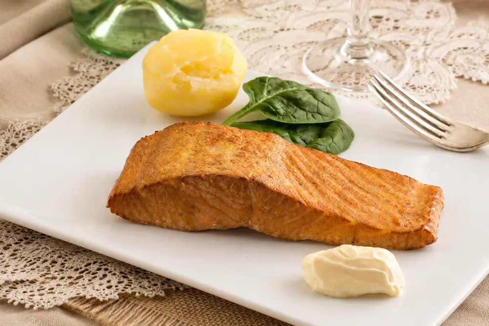 Tea smoked salmon plated with spinach leaves, boiled potato, and creamy aioli.