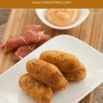 Crispy Serrano croquettes on a plate with paprika mayo and sliced ham.