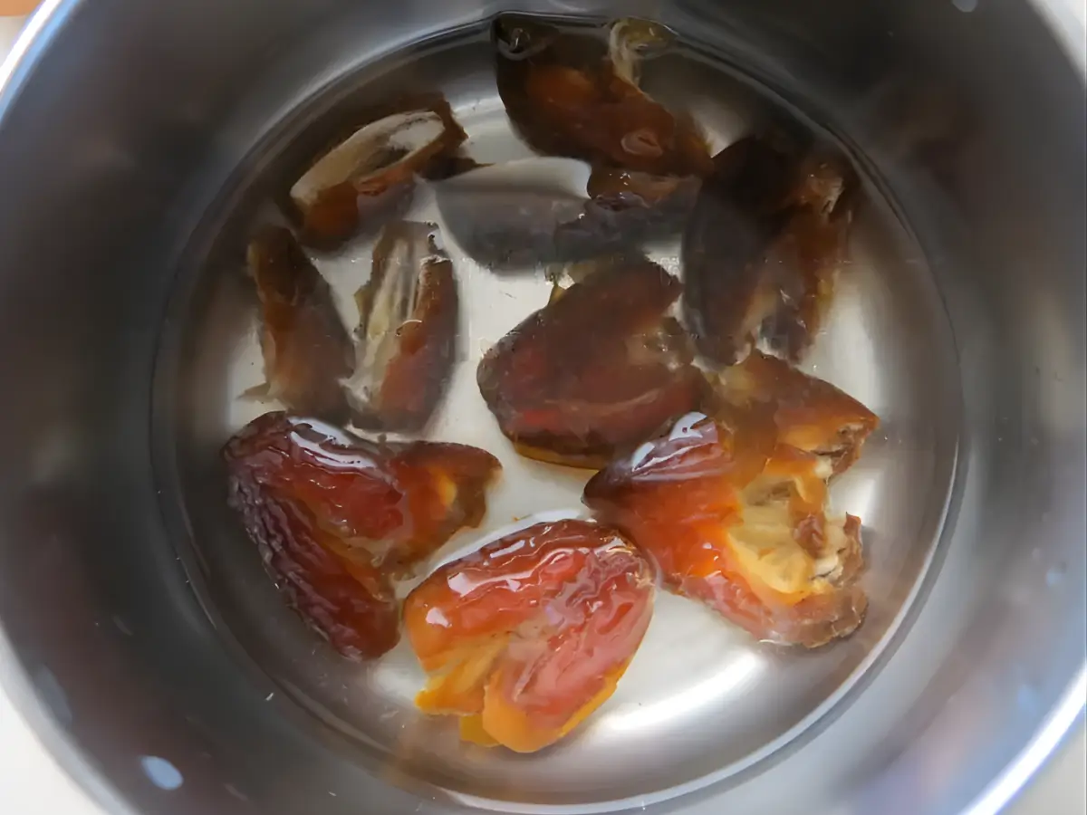 Pitted dates soaking in water in a saucepan before cooking.