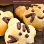 Baked Kitty Cat Bread Buns with chocolate dough facial details on a wooden surface.