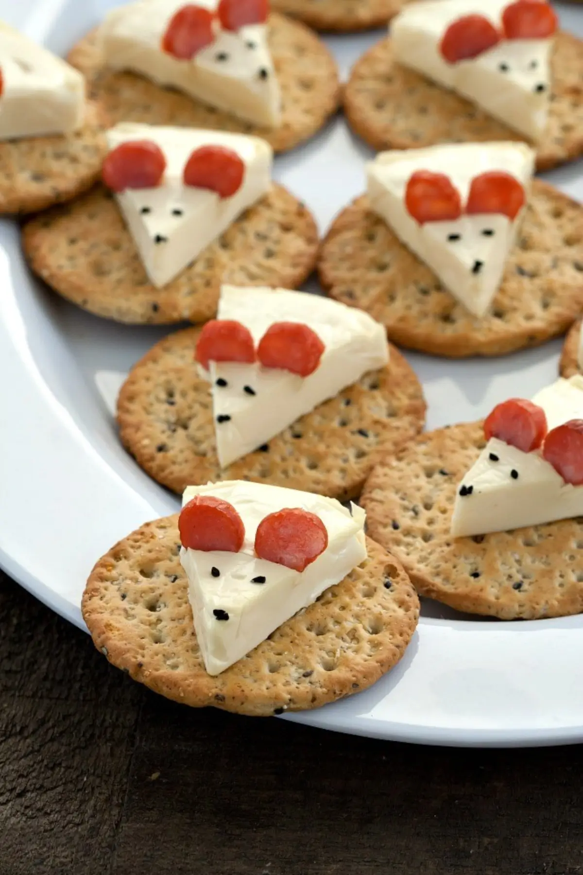 Cheese mouse made from a cheese triangle with salami ears on a cracker.