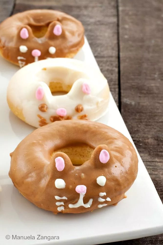 Close-up of decorated kitty cat doughnuts with pink ears and whiskers.