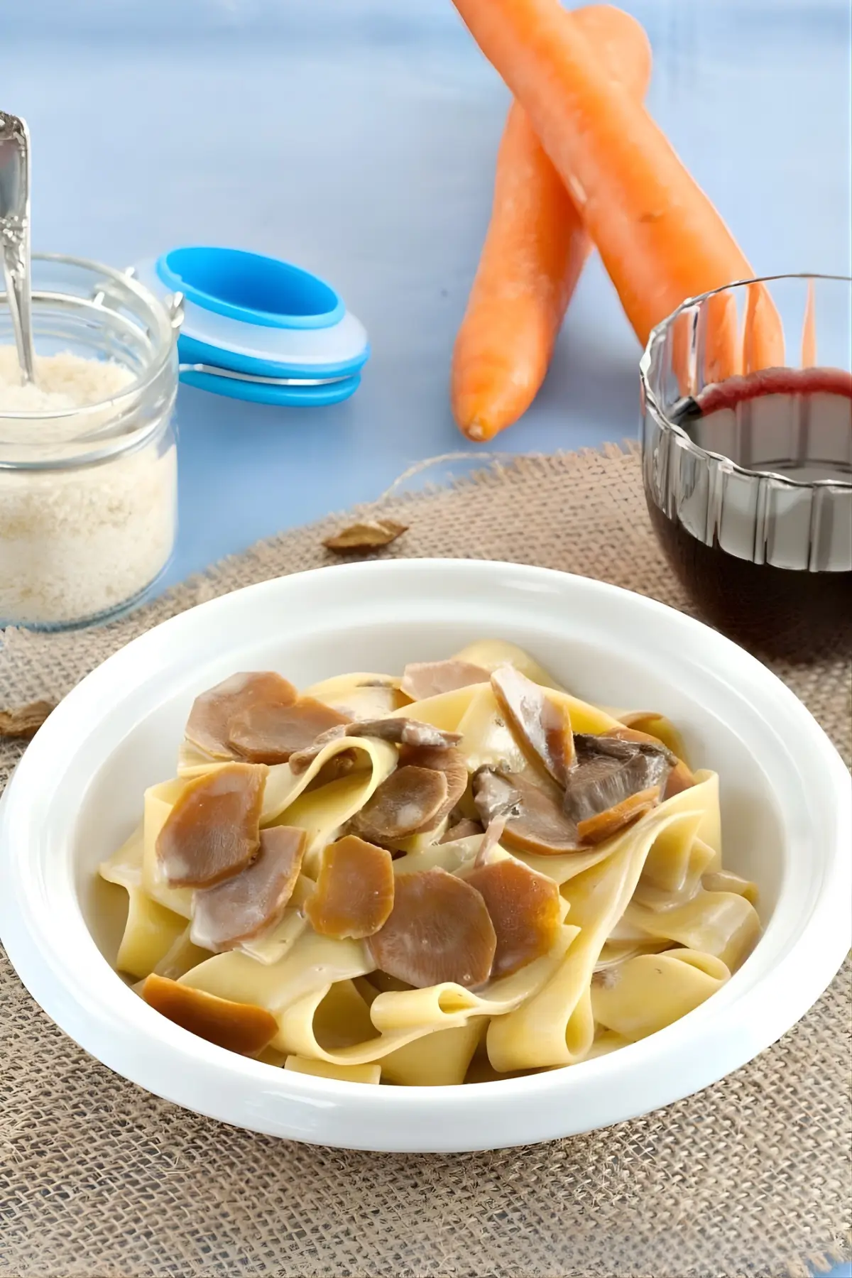 Finished plate of Pasta Contadina served with grated cheese and a glass of red wine.