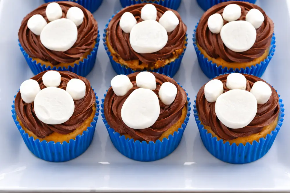Paw Print Cupcakes decorated with chocolate icing and marshmallow paw shapes arranged on a serving plate.