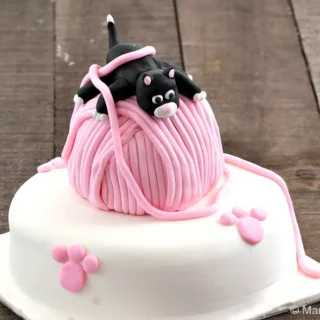 Finished Playful Kitten Cake featuring a black fondant kitten on a pink yarn ball and white fondant base.