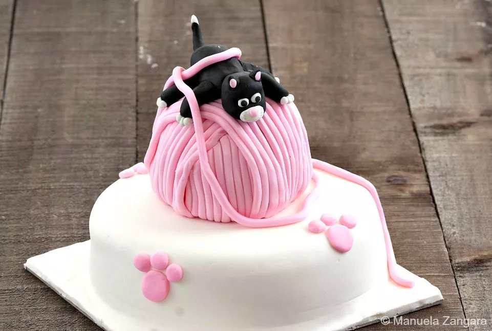 Finished Playful Kitten Cake featuring a black fondant kitten on a pink yarn ball and white fondant base.