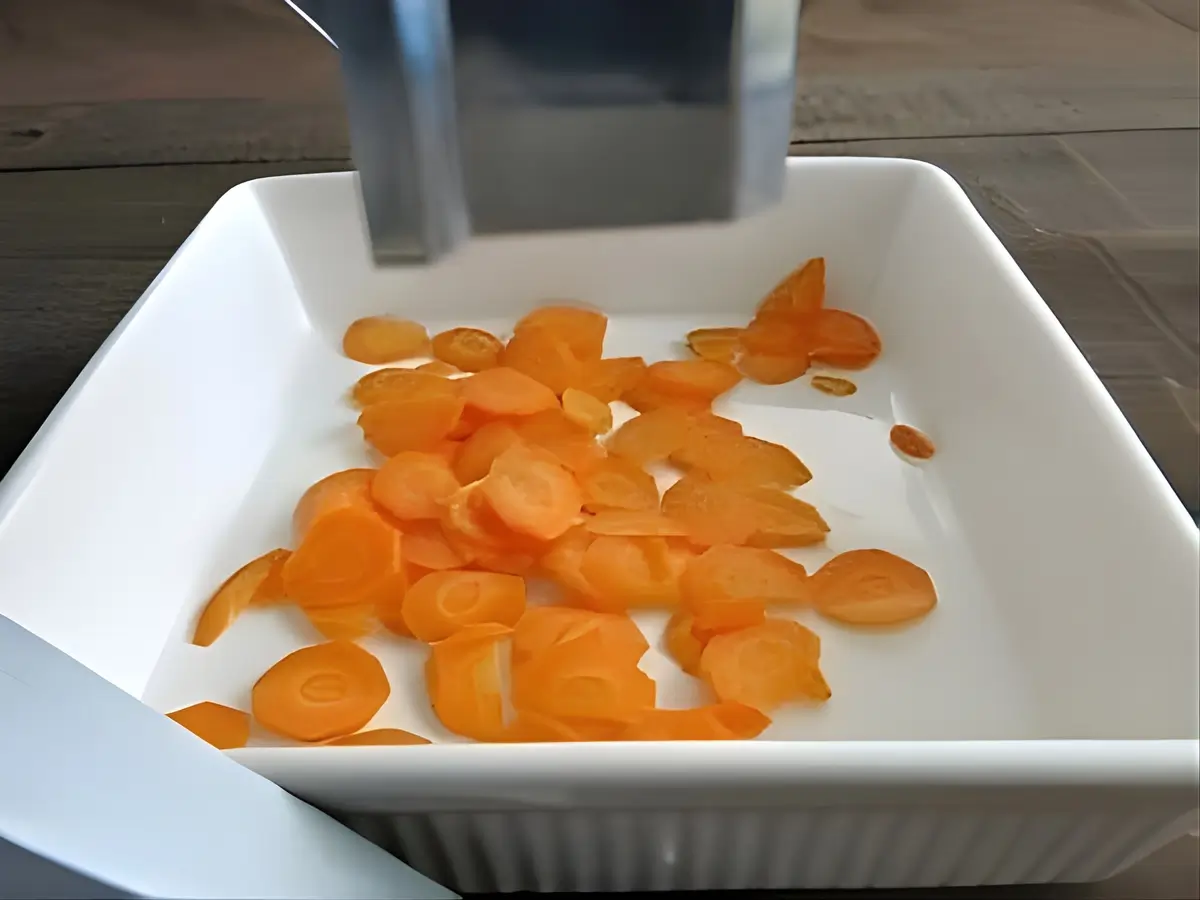 Freshly sliced carrots under the Toollio vegetable cutter.
