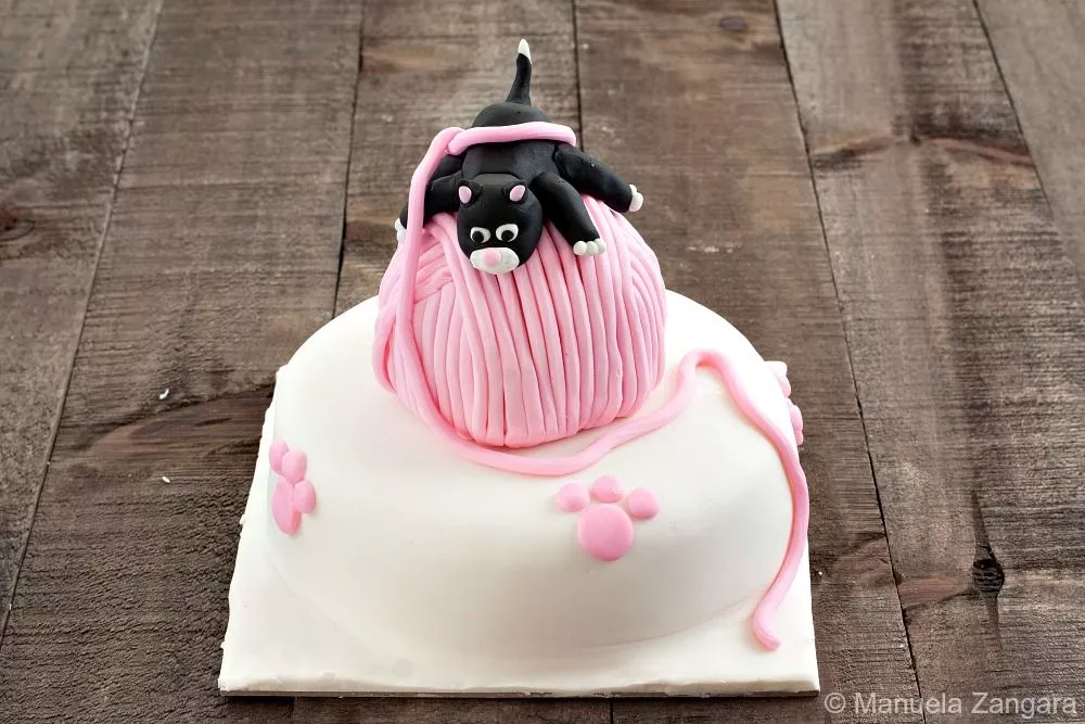 Full Playful Kitten Cake with pink paw prints and fondant yarn string draped along the side.
