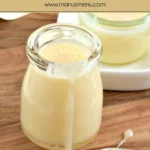 Homemade condensed milk in small jars with a spoon.