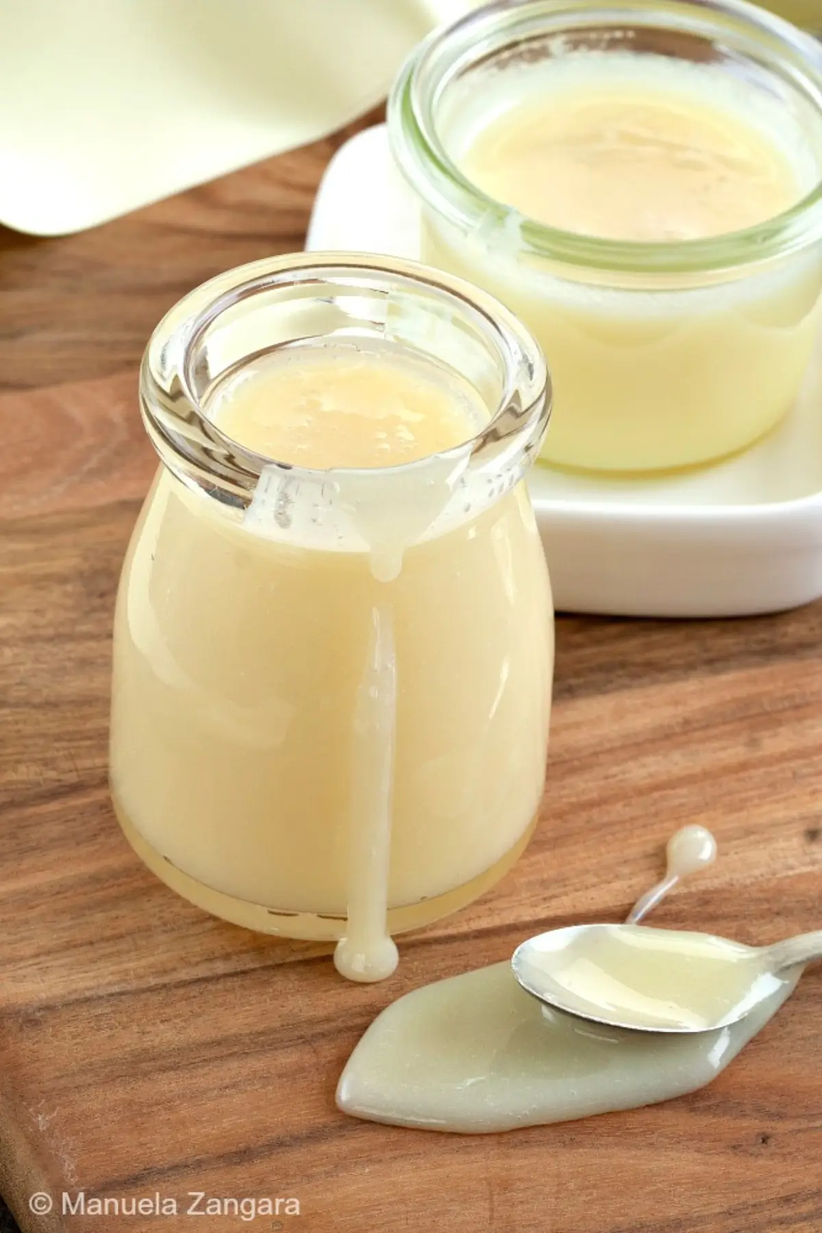 Homemade condensed milk in small jars with a spoon.