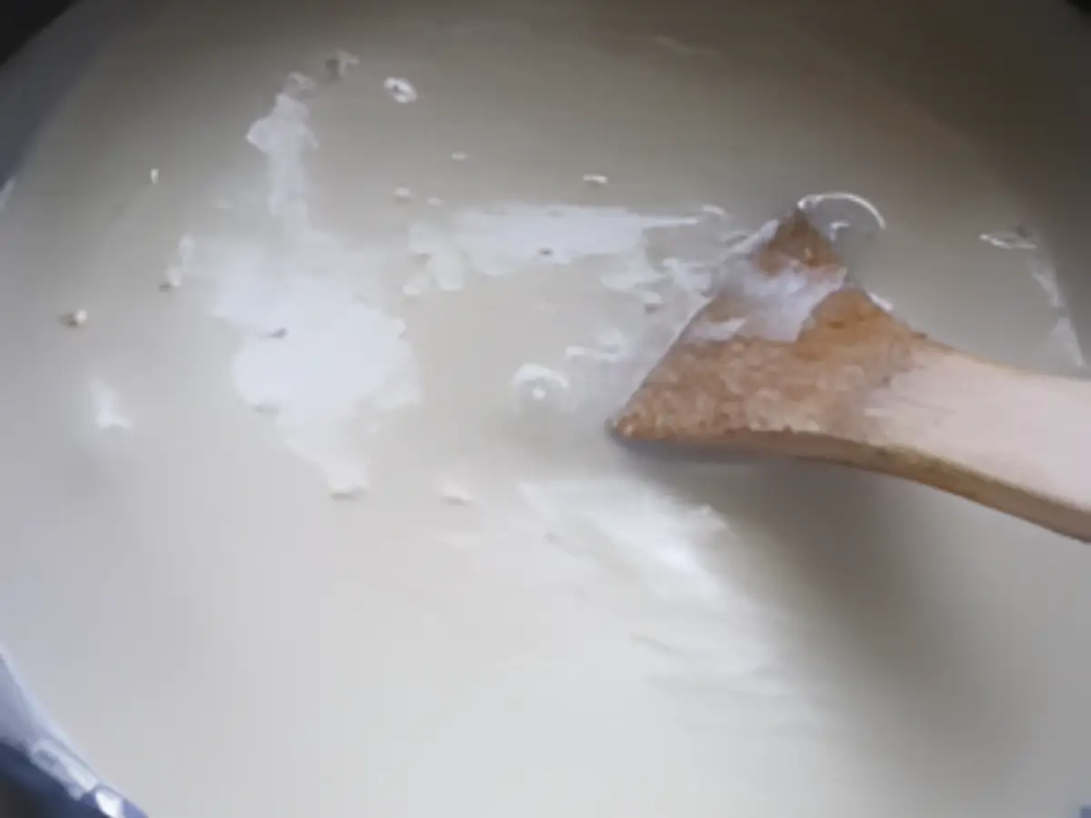 Milk simmering and turning frothy as it reduces.