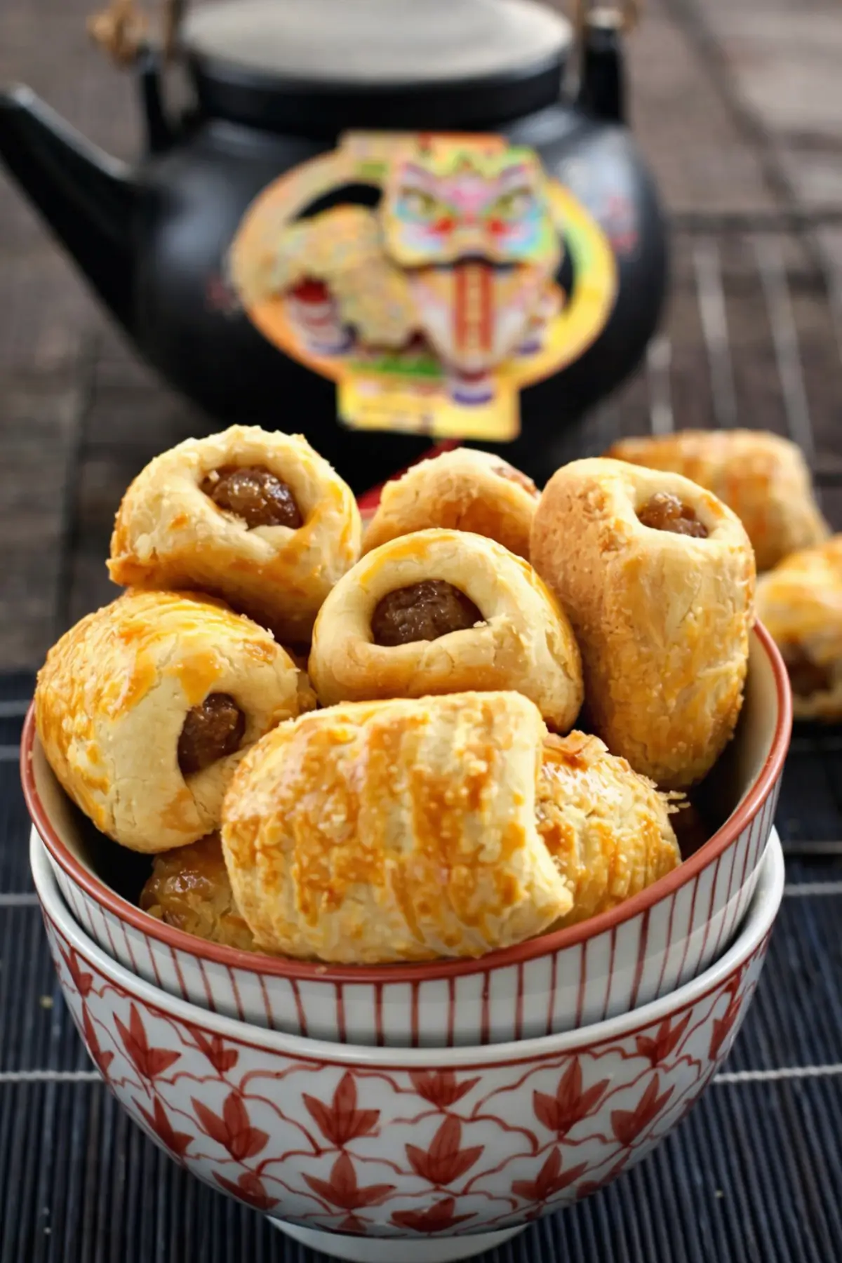 Bowl of golden pineapple tarts with crumbly pastry and sweet filling in the centre.