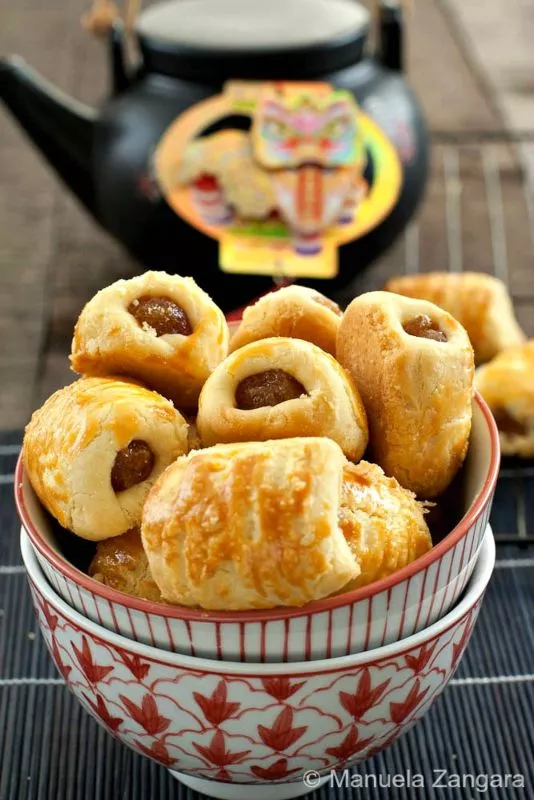 Golden pineapple tarts stacked in a bowl.