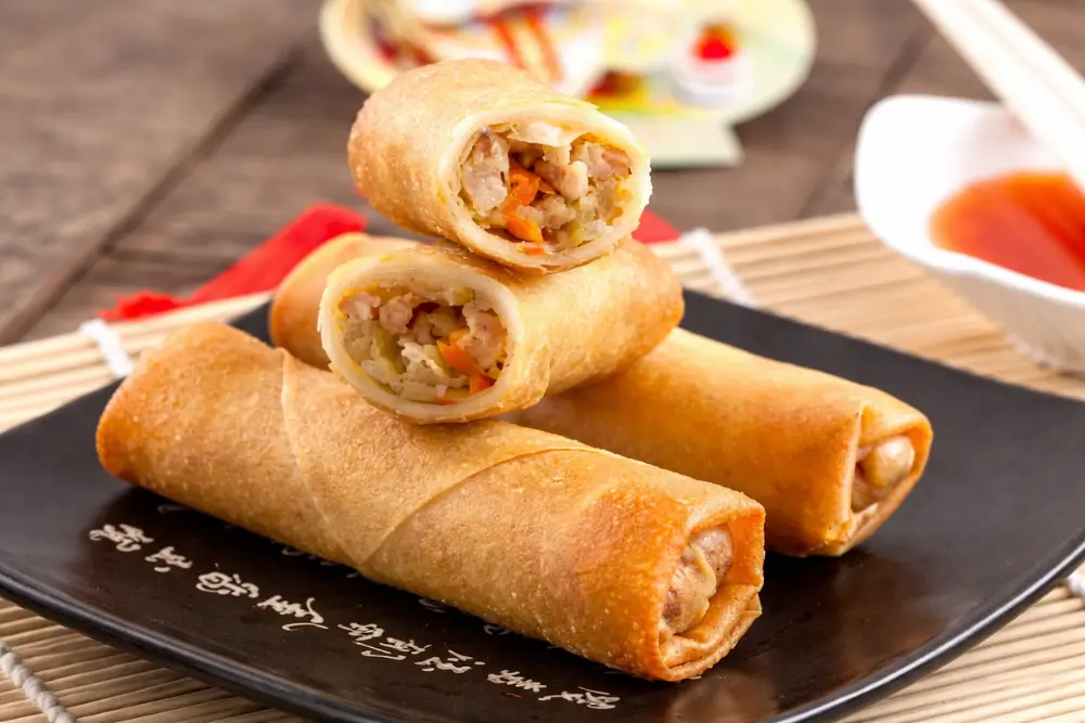 Crispy spring rolls sliced open to show the cooked chicken and vegetable filling.