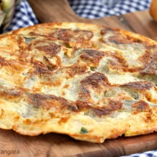 Close-up of a sliced Artichoke Frittata on a wooden board.