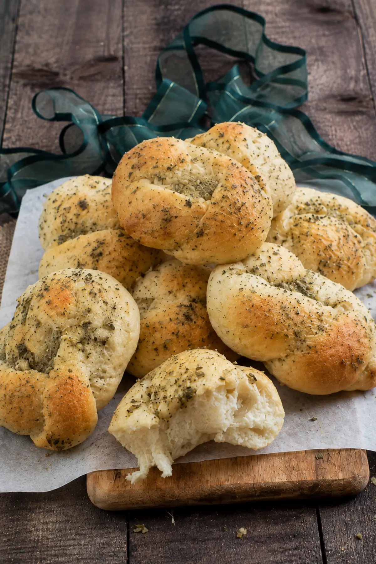 Golden Garlic Knots topped with herbs and served warm on a wooden board.