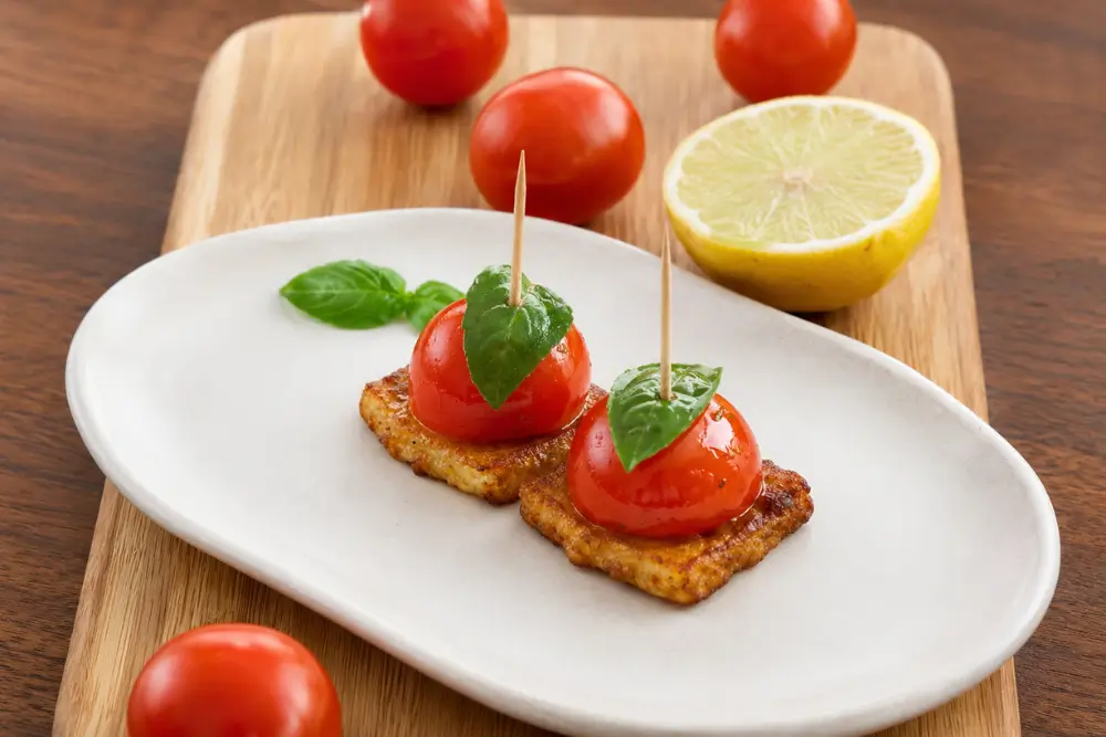 Halloumi appetisers with cherry tomatoes and basil presented on a serving board with lemon.
