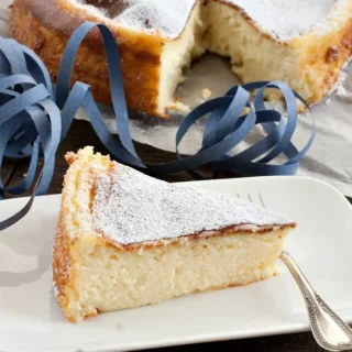 Close view of the baked cake topped with powdered sugar on a wooden table.