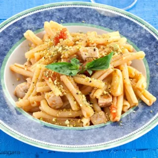Close-up of swordfish and pistachio pasta on a plate.