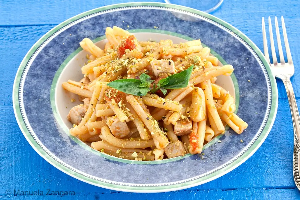 Close-up of swordfish and pistachio pasta on a plate.