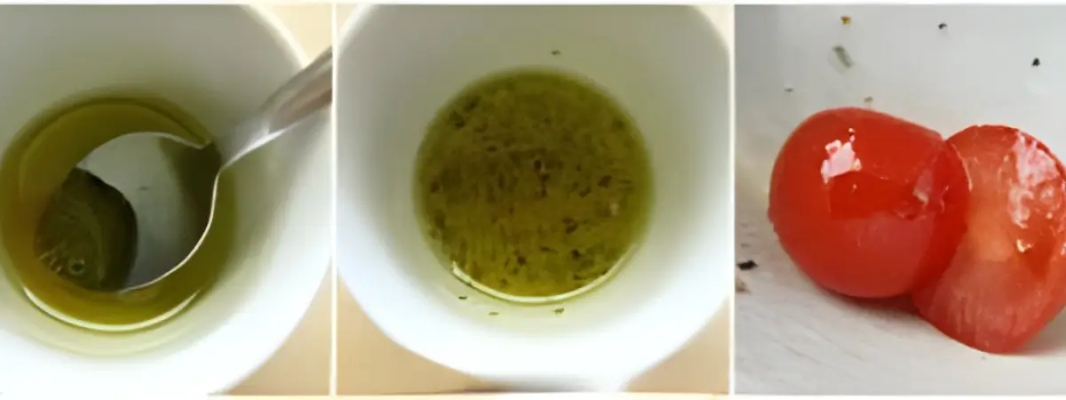 Olive oil vinaigrette being mixed in a bowl beside halved cherry tomatoes.