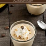 Chilled coffee mousse served in glasses with whipped cream, chopped hazelnuts, coffee beans, and spoons.