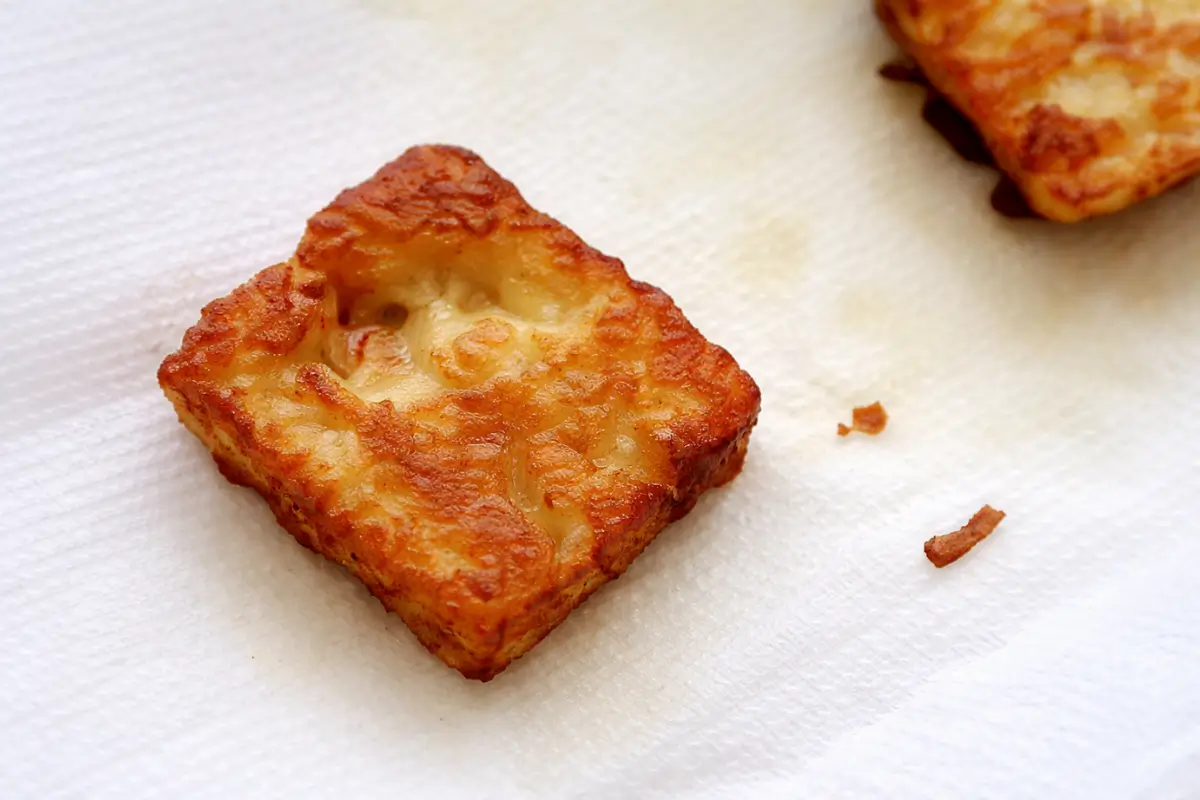 Golden fried halloumi resting on kitchen paper to absorb excess oil.