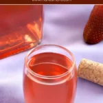 Glass of Fragolino strawberry liqueur beside a cork and fresh strawberries.