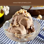 Creamy homemade hazelnut gelato in a glass bowl with chocolate drizzle and chopped nuts on top.