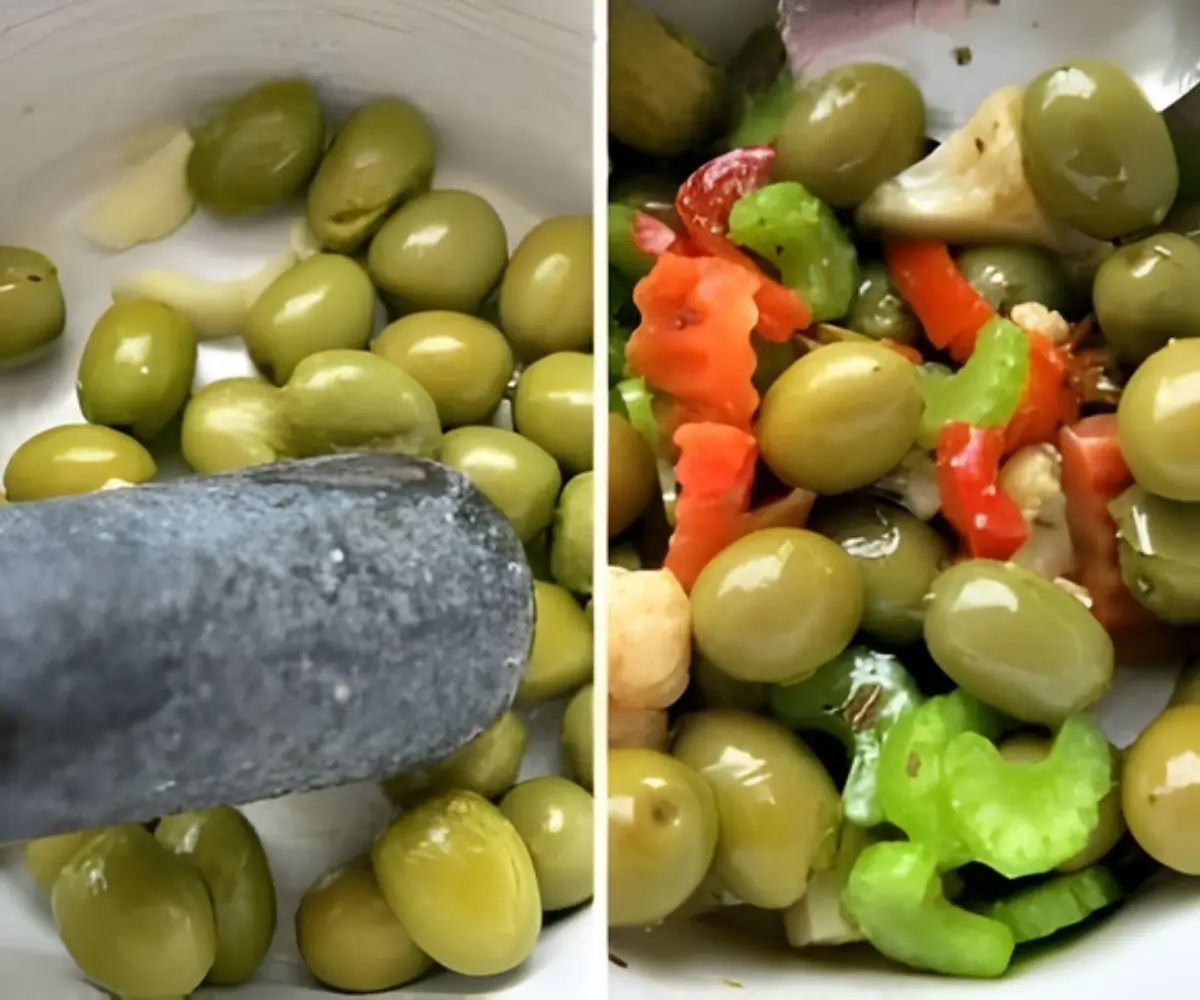 Green olives being cracked with a mallet and then mixed with vegetables in a bowl.